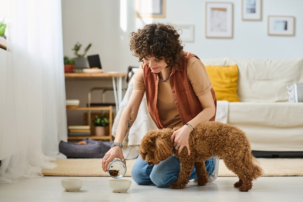 Woman feeding her dog food from a bowl