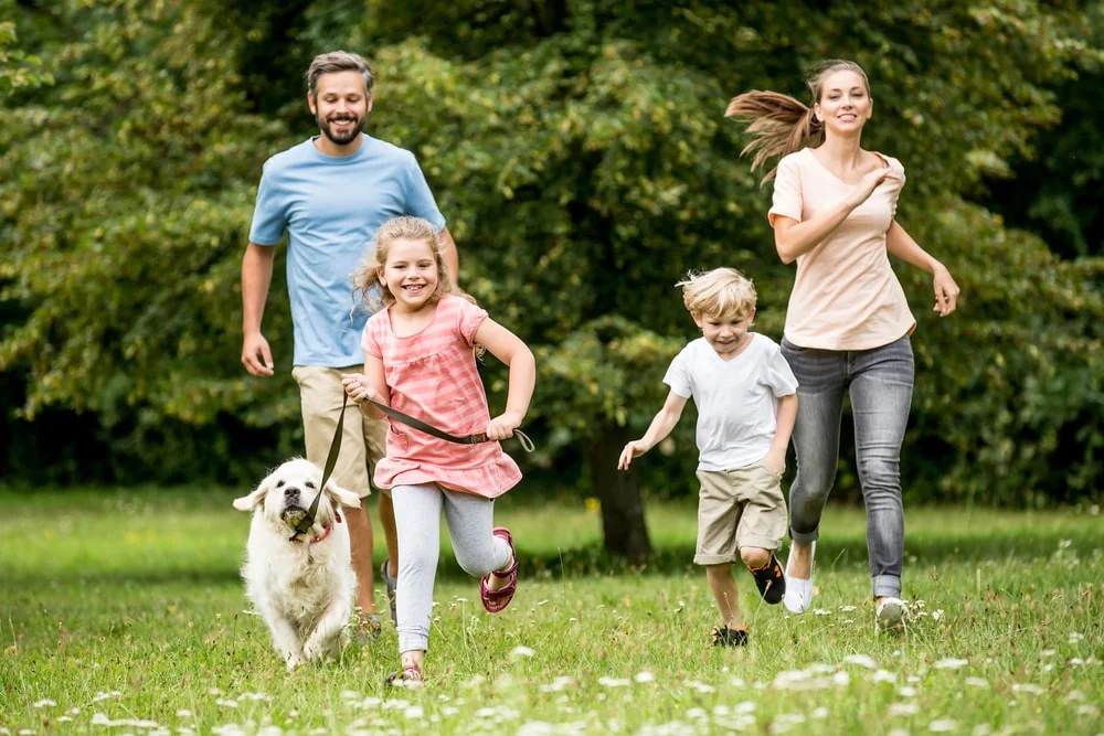 Family running through the field with their dog