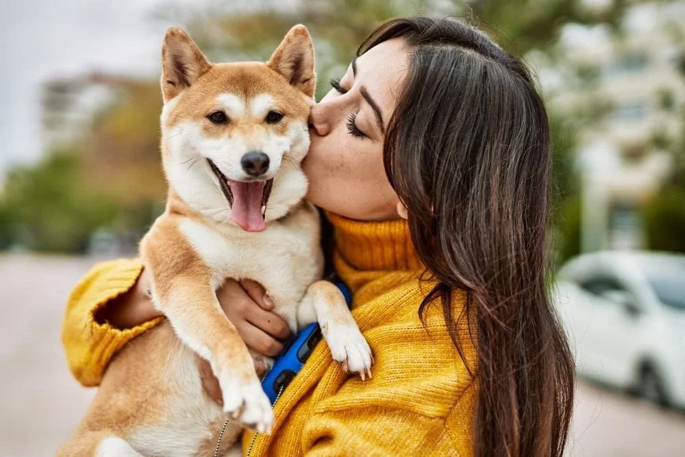 Woman kissing her dog on the cheek